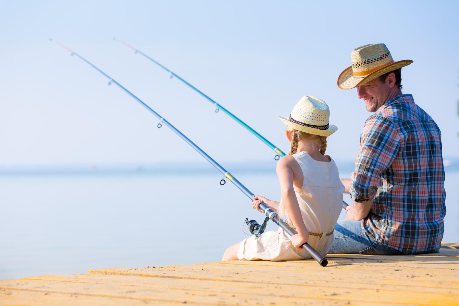 a father and daughter fishing on pier